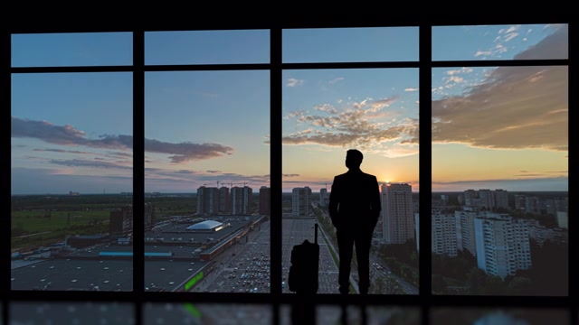 详情图-在清晨的城市背景下，提着箱子的男子站在室内。时间流逝