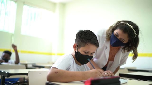 老师戴着口罩在学校帮助学生