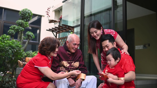 春节团圆饭后，亚洲华人家庭的老爷爷给孙子送红包红包，吃传统菜肴生鱼