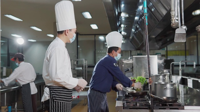 在酒店餐厅厨房里准备食物的厨师团队。食物和丁克概念。