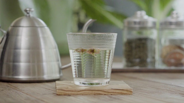 茶壶将热水倒入桌上的玫瑰茶杯中