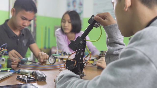 教育主题:聪明的学校男孩建立一个小机器人手臂和使用笔记本电脑编程软件的机器人工程类作为学校科学项目。科学与人的观念。