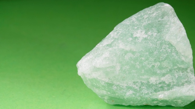 这种石头是一种砾石的特写。绿色背景上的金块。