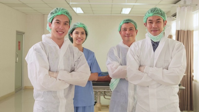 治疗冠状病毒感染患者后亚洲医生摘下防护口罩。肖像医务人员在个人防护用品和擦洗脱下口罩的心情愉快和高兴的微笑在医院。