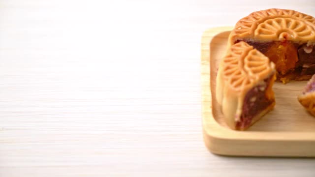 中国月饼紫地瓜和蛋黄味的茶在木盘上