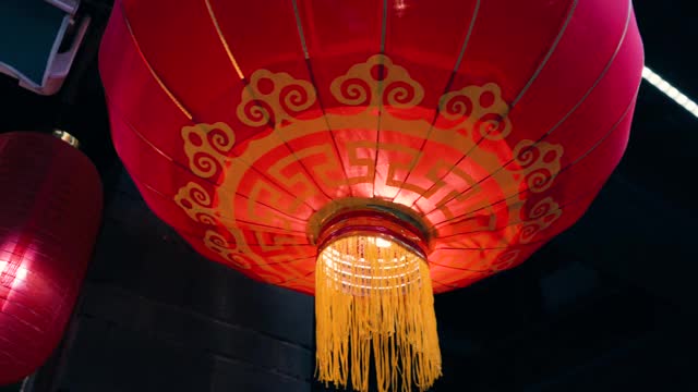 从屋顶上悬挂在老建筑边缘的传统红色球形中国灯笼，黄色的灯光从里面照亮四周。为国庆做准备。