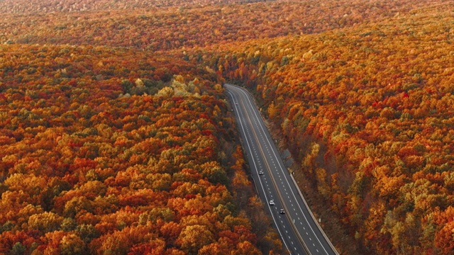 高速公路上的群山在清晨，夕阳刚落，就进入了五彩缤纷的秋季。无人机视频与加速平移摄像机运动。