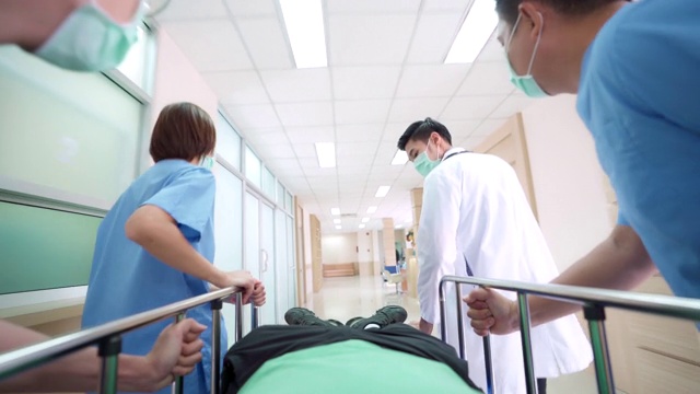 4K超高清缩小视角低角度拍摄:病人在医院轮床担架床上被医疗团队运送到医院走廊。