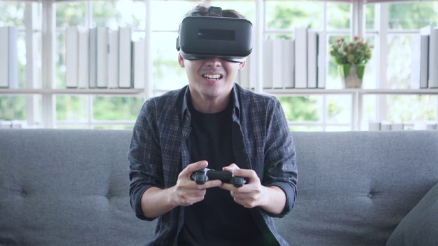 亚洲年轻人用VR眼镜和遥控器玩游戏