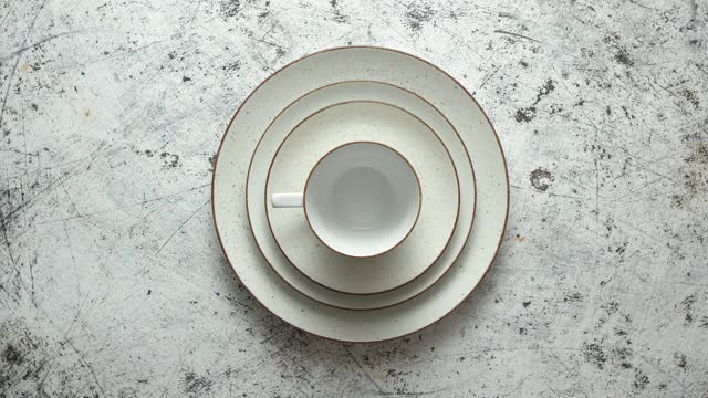 在质朴的白色背景上的一套陶瓷餐具。有不同大小的盘子，碟子和杯子