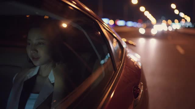 女人用电话在汽车里通过城市晚上回家
