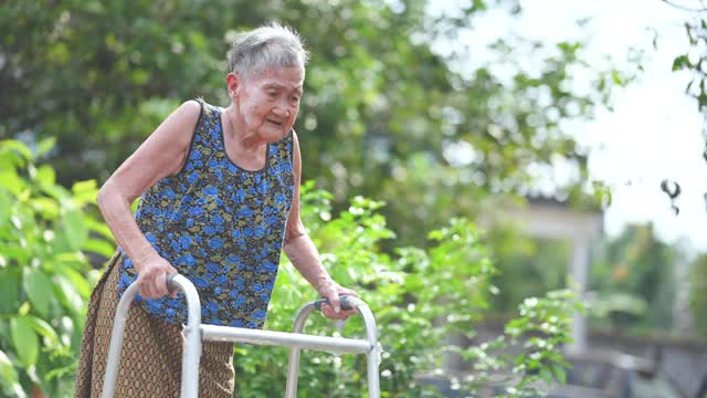 在花园户外学习如何拄着拐杖走路的中国老年妇女