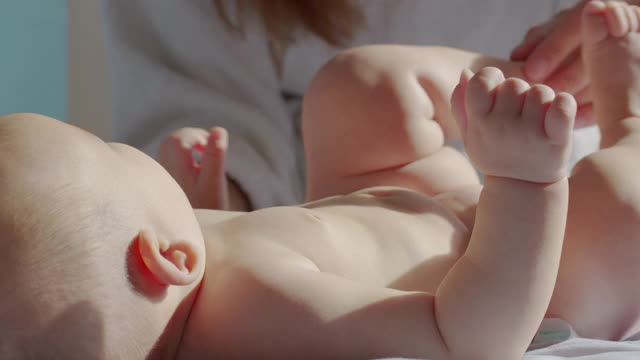 妈妈晚上给婴儿换尿布。美丽的白人女孩妈妈给她的小孩换尿布。特写镜头。