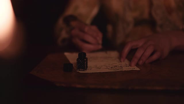 羽毛笔和墨水在烛光下。