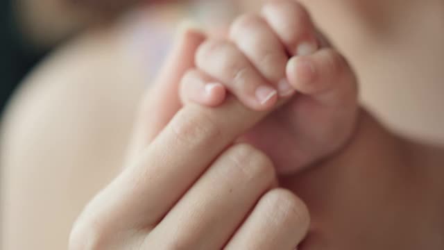 母亲手牵着新生婴儿的手