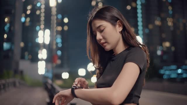 女运动员在晚上跑步训练时使用科技设备
