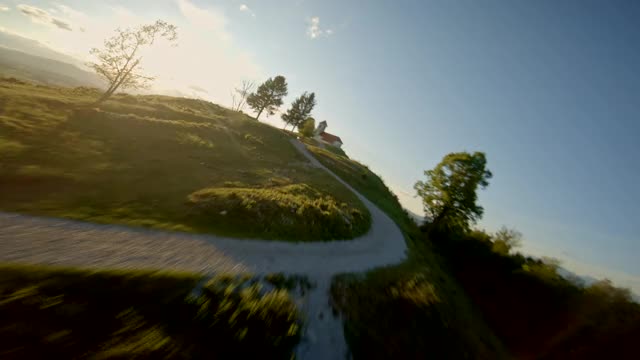 空中竞速无人机沿着通往山上教堂的道路飞行