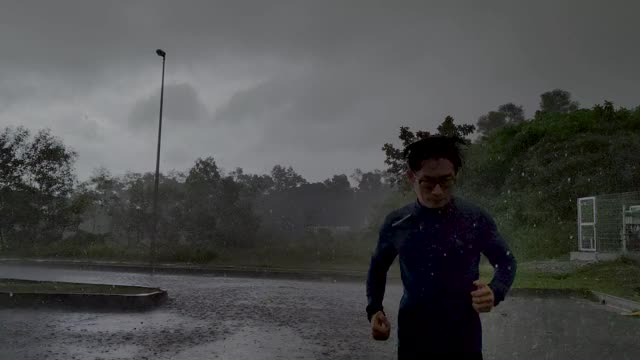 一个穿着运动服的亚洲华人运动员在雨中在街道上慢跑