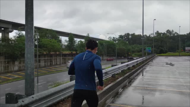 一个穿着运动服的亚洲华人运动员在雨中在街道上慢跑