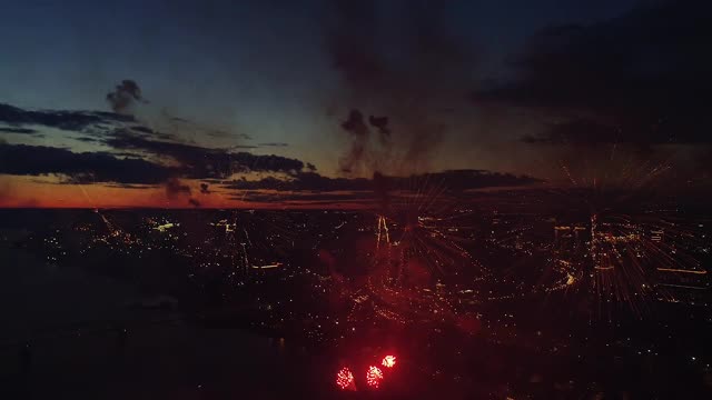 鸟瞰图烟花城市天空。除夕夜无人机飞行现场。城市庆祝灯光。飞行在火花烟花爆炸的节日。明亮的爆炸烟花在晚上城市天际线背景