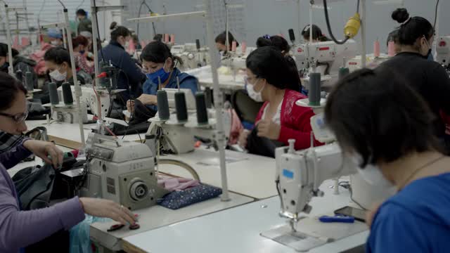 在纺织工厂的缝纫工场工作的体力女工都戴着防护口罩