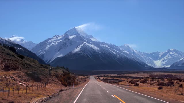 一條又長又直的路通向一座巨大的雪山。去新西蘭庫克山的路。(觀點)