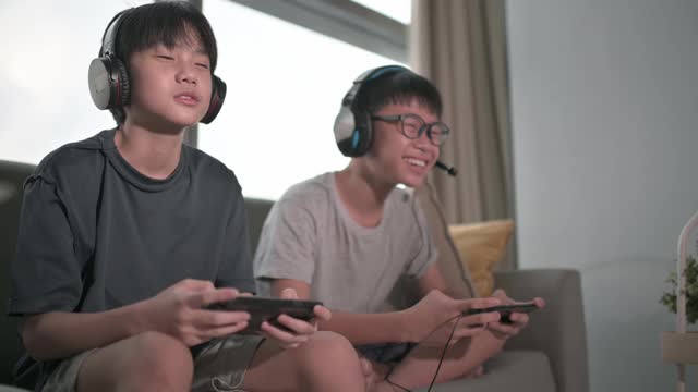 两个华裔少年放学后在客厅玩电子游戏