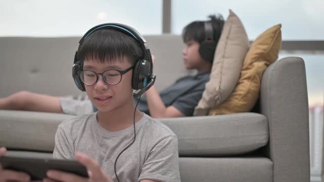两个华裔少年放学后在客厅玩手机游戏