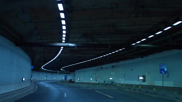 一辆车在夜间行驶在高速公路的隧道里