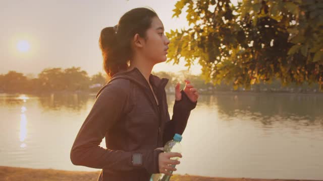 迷人的亞洲少女在公園里跑步。年輕女子晨跑鍛煉。