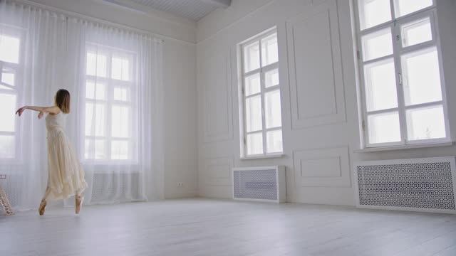芭蕾舞演员穿着尖头鞋和白色飘动的裙子在一个明亮的舞厅跳舞，旋转和跳跃高