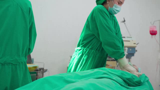 医院手术室的一组医生。亚洲专业的外科医生和护士团队为重症监护患者实施心肺复苏术，并在手术中使用除颤器电击心脏。