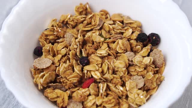 慢动作牛奶倒进一个白色的杯里和麦片