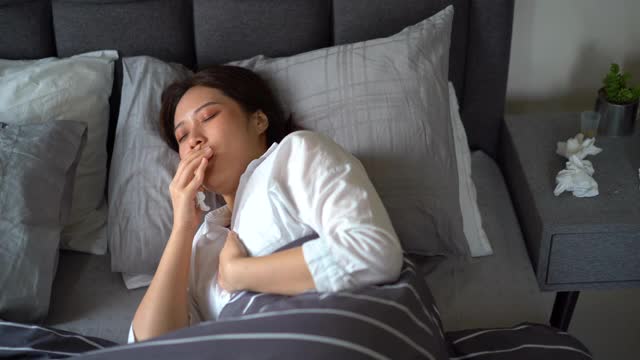 年轻的亚洲女人生病的病人咳嗽和打喷嚏在床上