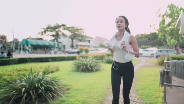 年轻的亚洲女性在公园内跑步在日落黄金时间，健康的现代女性生活方式，运动动机自我努力，减肥工作常规，营养卡路里摄入控制