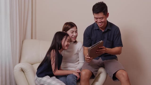 詳情圖-亞洲快樂的父母和漂亮的女兒在客廳里一起使用平板電腦享受家庭時光。