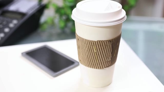 詳情圖-一杯咖啡，把手機放在筆記本電腦上。
