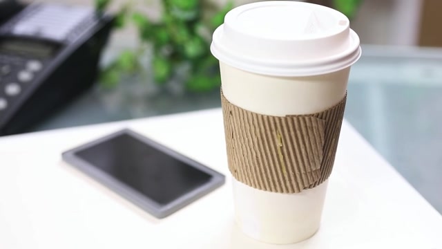 詳情圖-一杯咖啡，把手機放在筆記本電腦上。