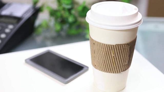 詳情圖-一杯咖啡，把手機放在筆記本電腦上。