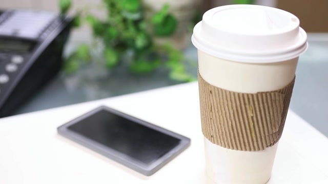 詳情圖-一杯咖啡，把手機放在筆記本電腦上。