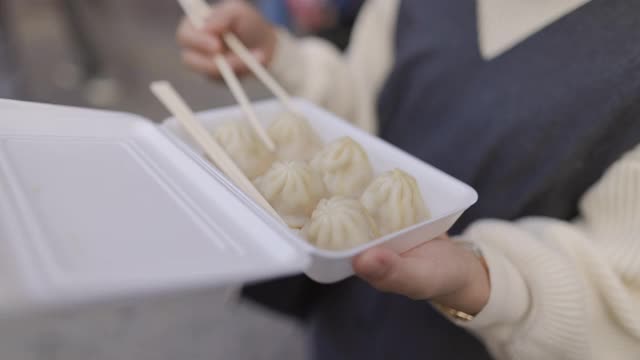 年轻女子在街上吃“小笼包”汤包