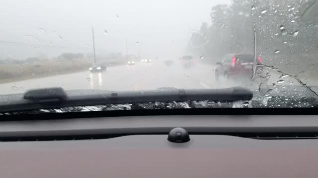 在暴雨中，高速公路司机POV穿过雨滴汽车的挡风玻璃。