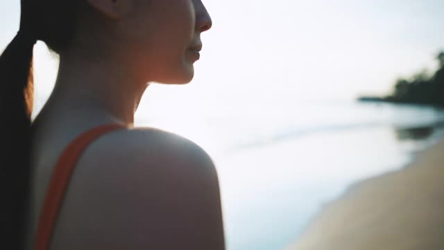 亚洲运动女性使用智能手表监测她在海滩上的跑步表现