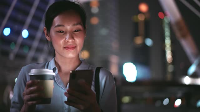亚洲商业女性在城市的夜晚使用电话