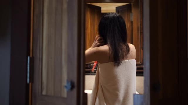 一个年轻女子在浴室里晾干头发。她正准备出门