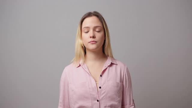 情绪激动的女人穿着粉色衬衫耸了耸肩对着镜头摆姿势