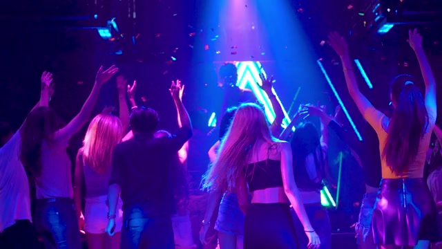 详情图-在音乐晚会音乐会上欢呼的人群。男男女女在地板上跳舞，音乐家在舞台上表演，灯光效果。年轻人在俱乐部里聚会，享受夜生活。