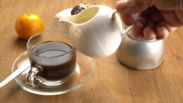 詳情圖-將新鮮牛奶倒入玻璃杯中的黑咖啡中，放在木桌上，配上成熟的橘子和巧克力松餅