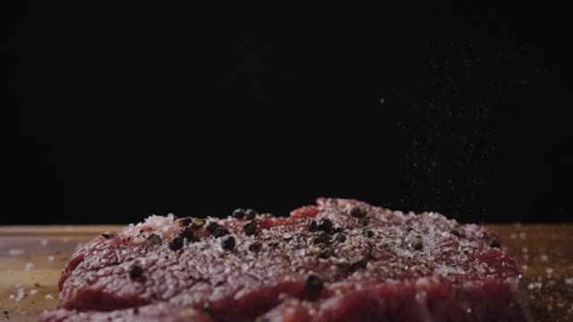 用慢动作将黑胡椒洒在牛排上