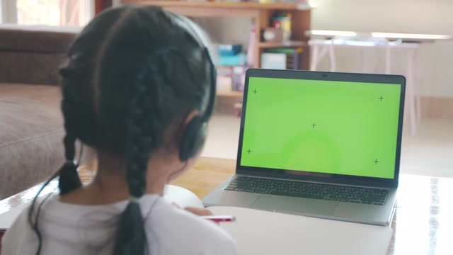 详情图-亚洲女童学生戴上耳机，通过视频电话与老师在线学习。由于Covid,-,19大流行，在隔离期间，孩子正在用电脑笔记本电脑在家学习。